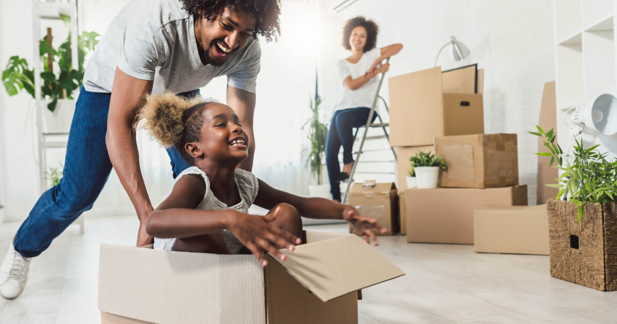 Family with child having fun in moving box while relocating to new home