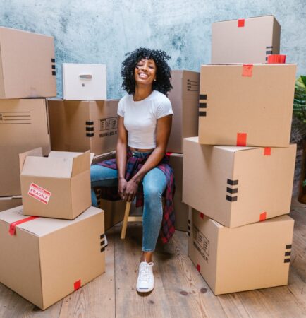 Woman sitting with labeled moving boxes ready for relocation and packing services