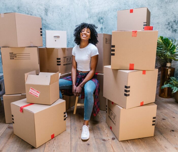 Woman sitting with labeled moving boxes ready for relocation and packing services