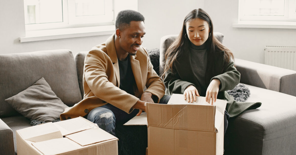 Young couple unpacking cardboard boxes in new home after stress-free move