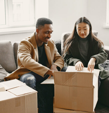 Young couple unpacking cardboard boxes in new home after stress-free move