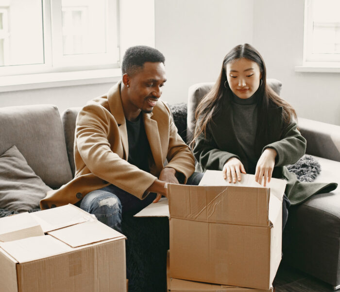 Young couple unpacking cardboard boxes in new home after stress-free move
