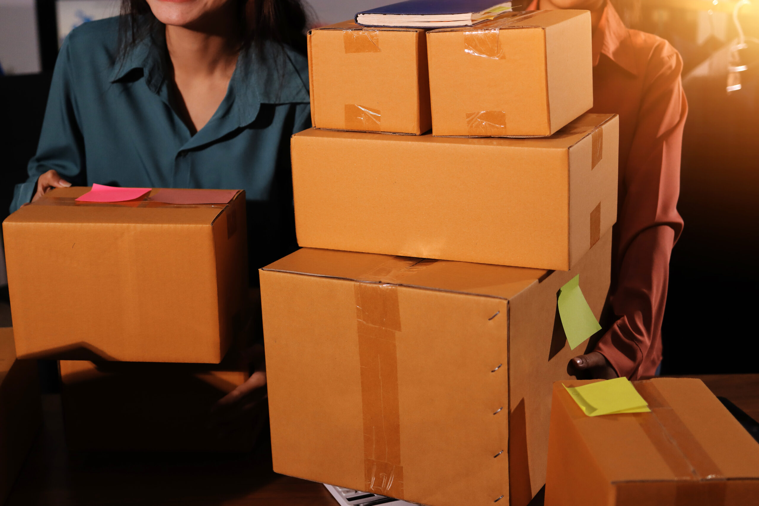 Business women carrying stacked moving boxes for office relocation and business moving services