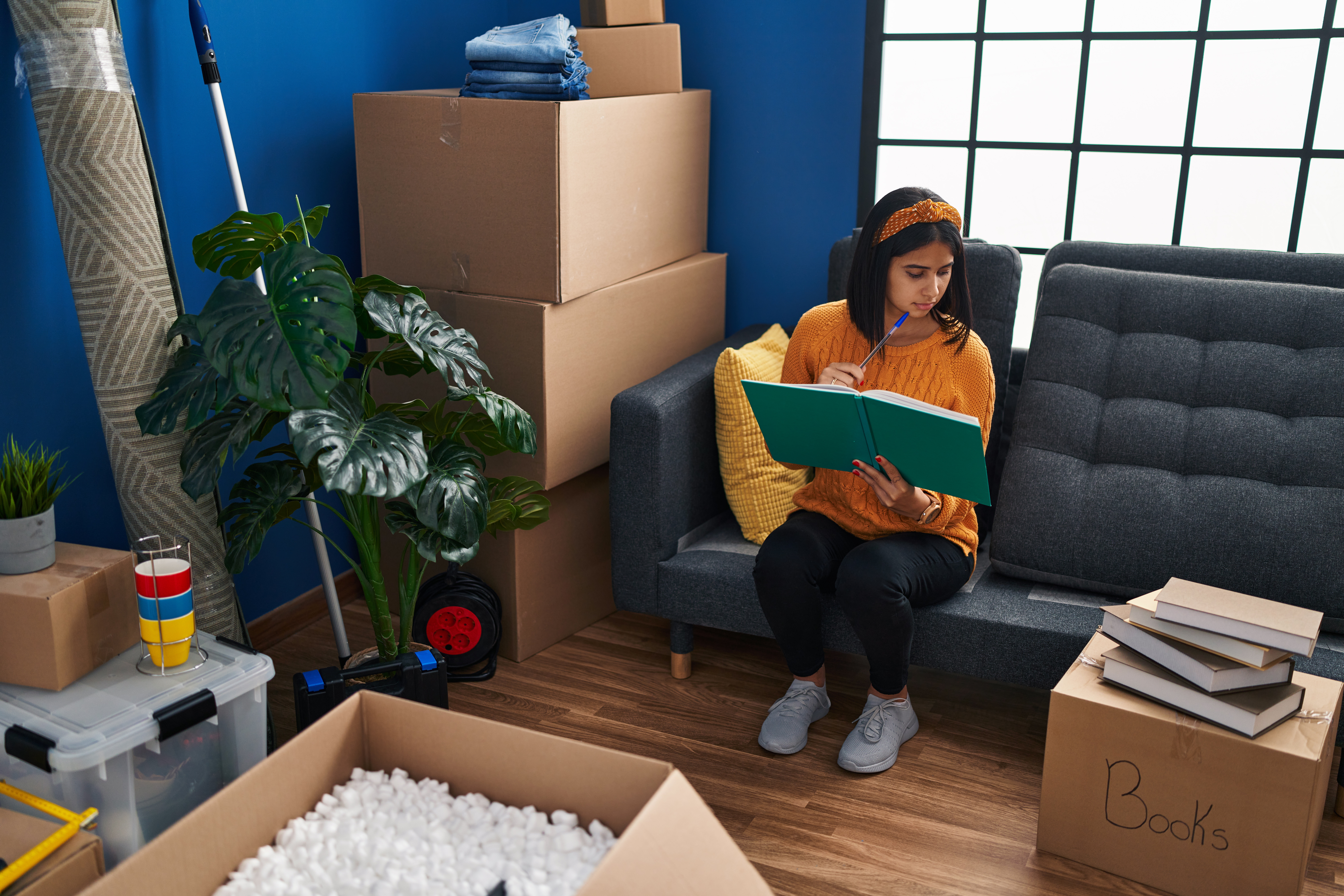 Young woman reading book while sitting on sofa in new home after relocating
