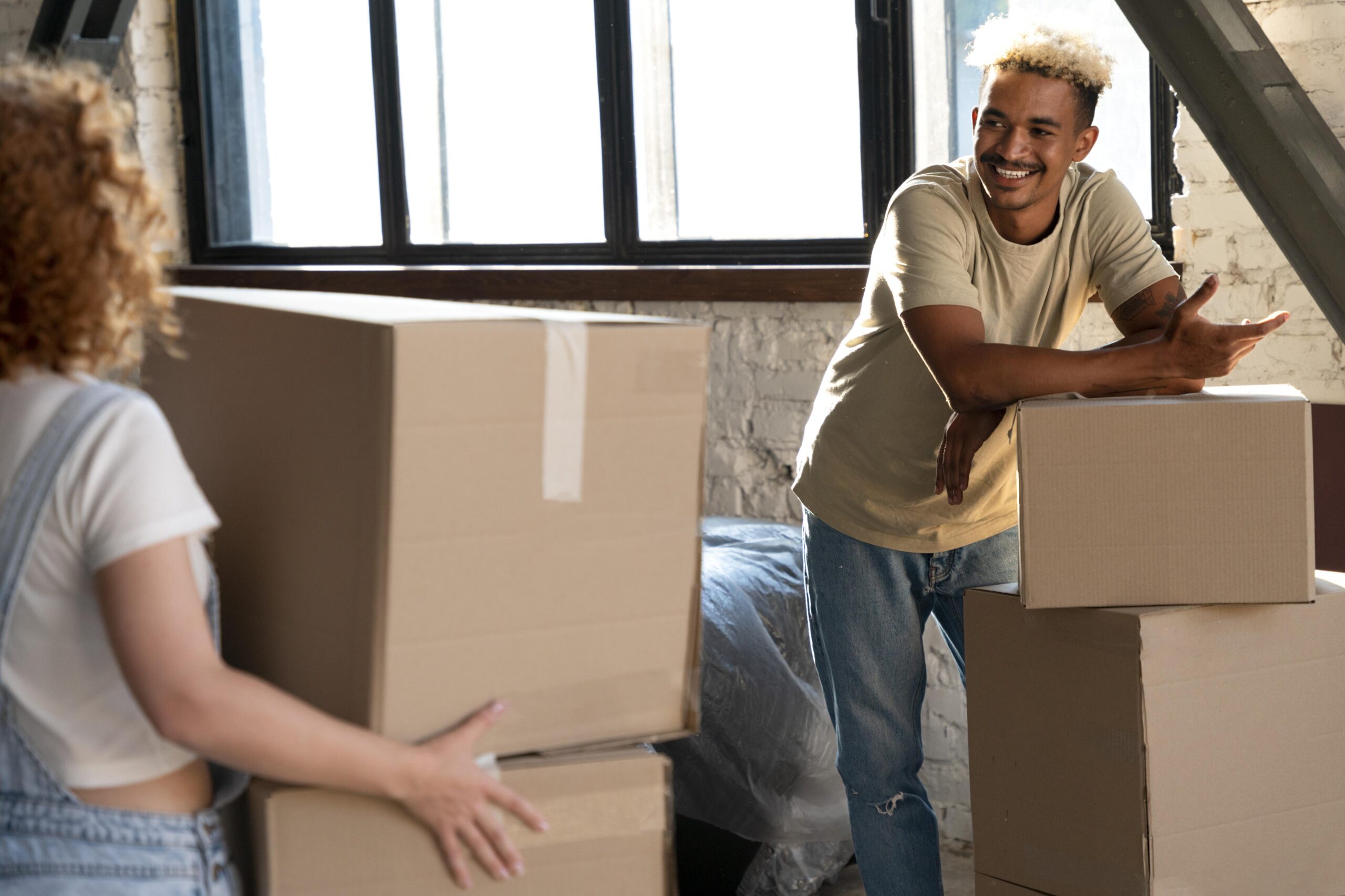 Happy couple handling cardboard boxes together moving into new home smiling