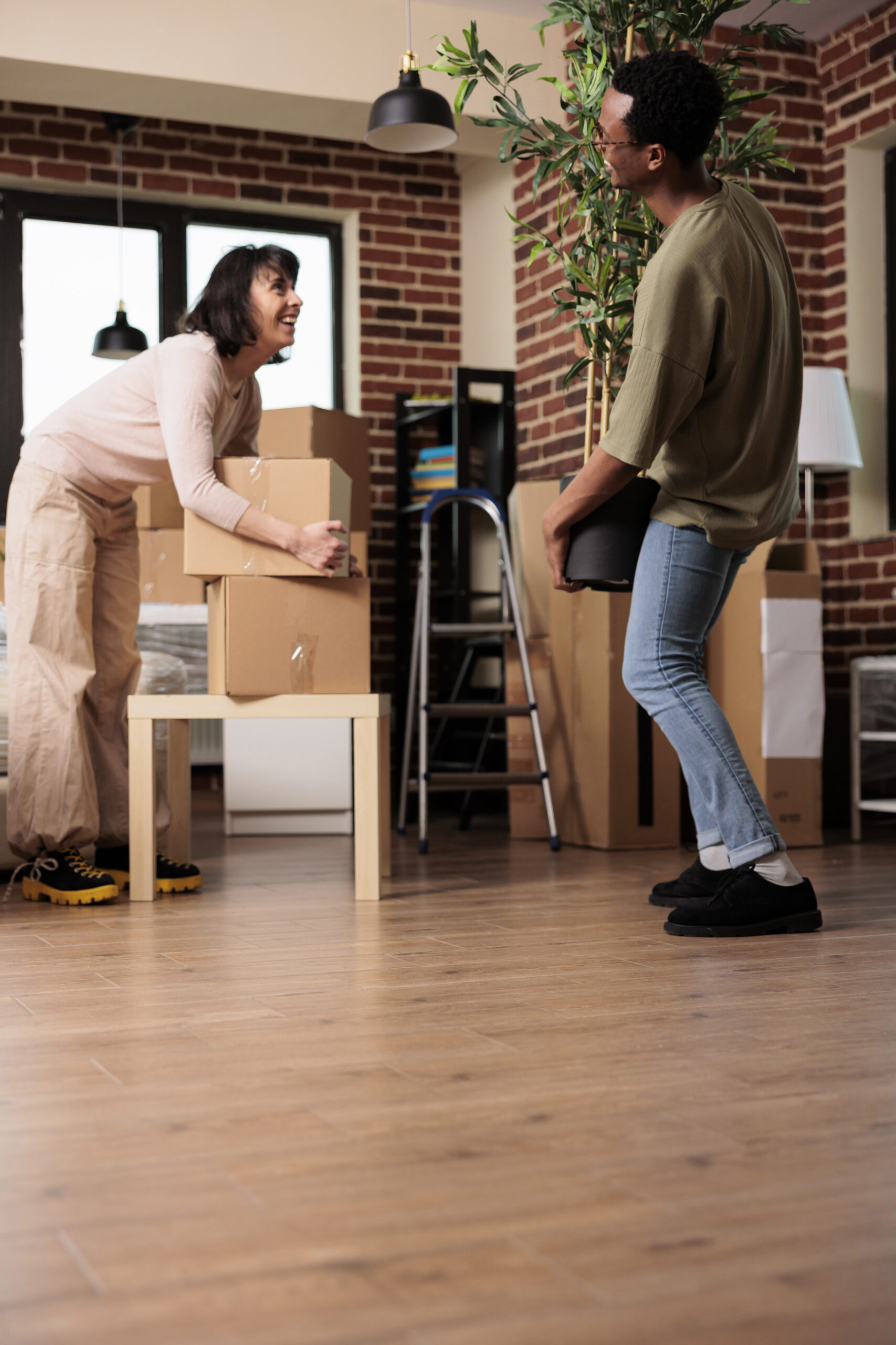Diverse couple moving into first apartment unpacking belongings and decorating new home